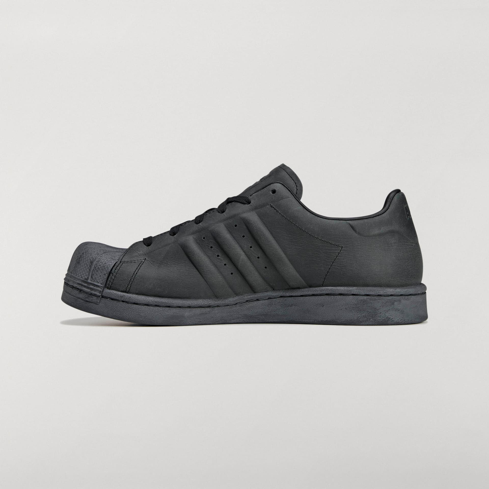 Side profile of the all-black adidas Originals by Avavav Modified Superstar, highlighting its reshaped sole and shell toe.