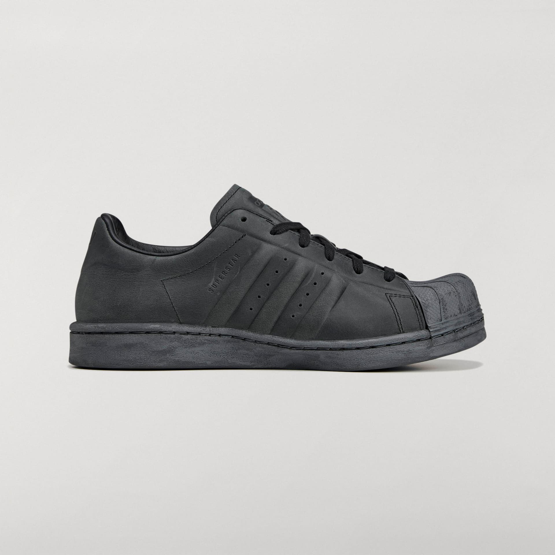 Side profile of the all-black adidas Originals by Avavav Modified Superstar sneaker against a plain studio background.