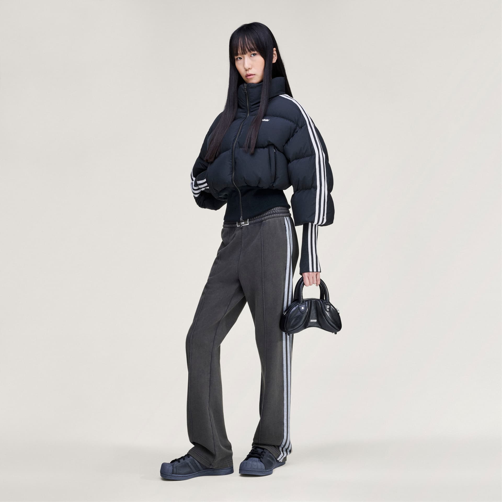Full-length shot of a model wearing the adidas Originals by Avavav Baby Puffer jacket with coordinating track pants.