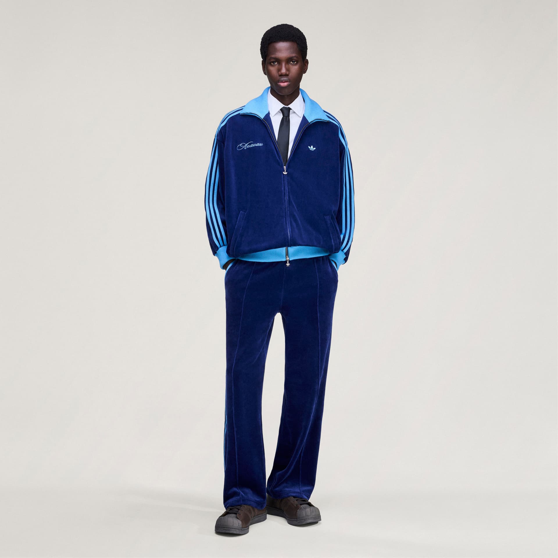 A model shown from the front wearing the adidas Originals by Avavav blue velvet track jacket with matching velvet trousers.