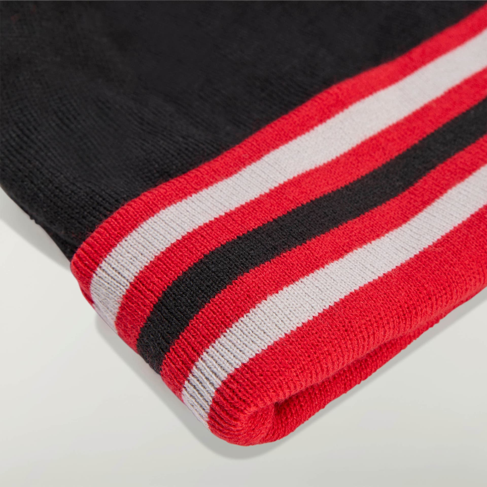 Close-up of the adidas Originals by Avavav Beanie, showcasing the detailed black, red, and white striped knit.