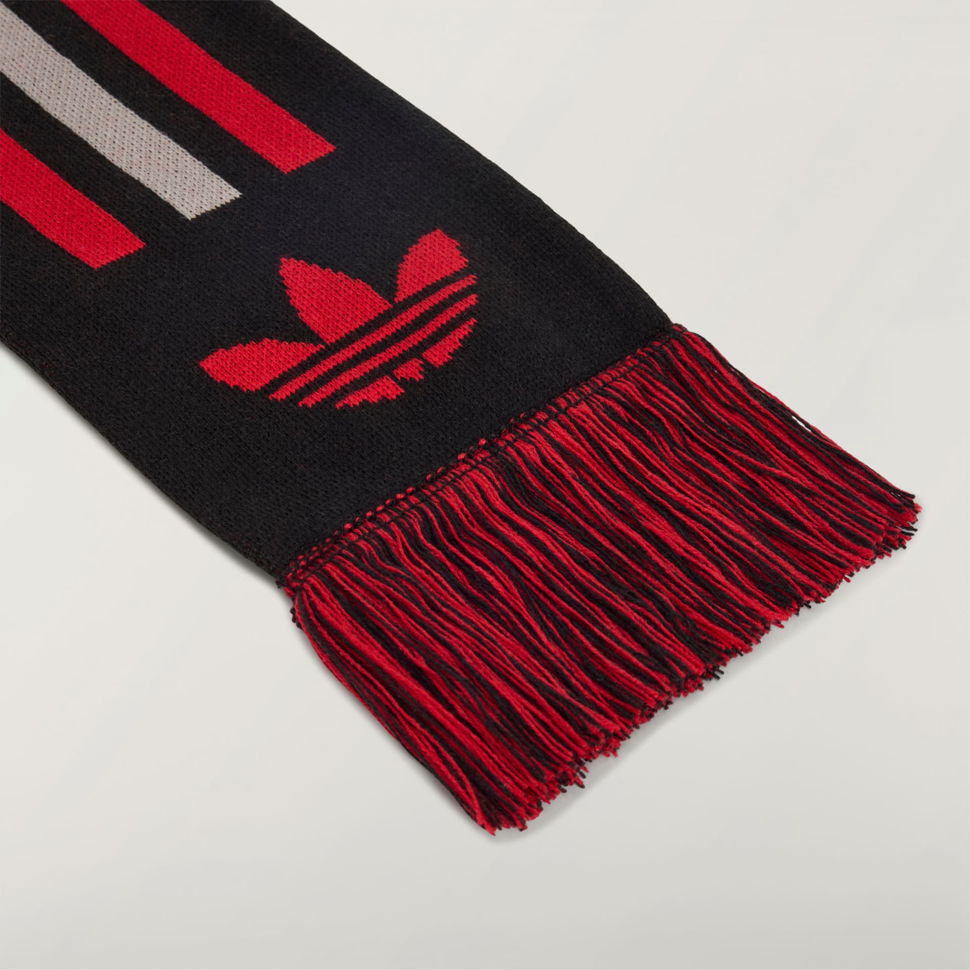 Detail shot of the fringed end of the black adidas Originals by Avavav Scarf, featuring a red trefoil logo and stripes.