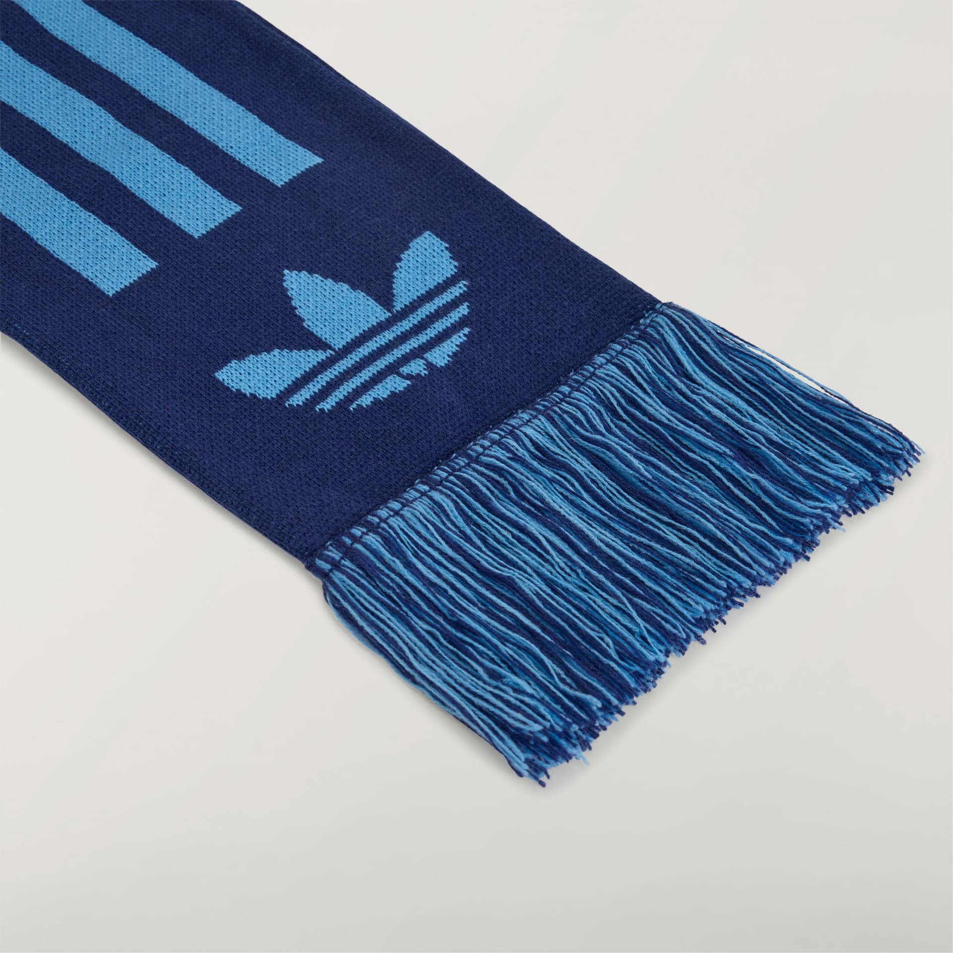 A close-up detail of the adidas Originals by Avavav Scarf in dark blue, highlighting the light blue logo and fringe.