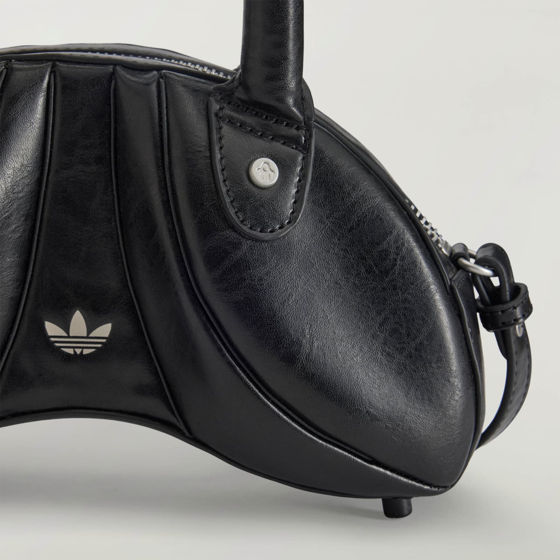 Close-up of the black adidas Originals by Avavav Sculpted Mini Bag, highlighting its curved silhouette and logos.